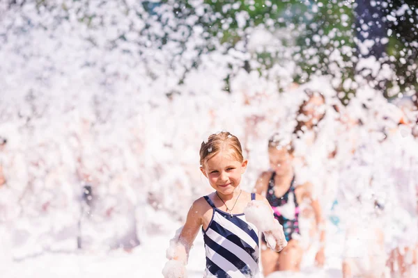 Cute little girl having fun at foam party. — Zdjęcie stockowe