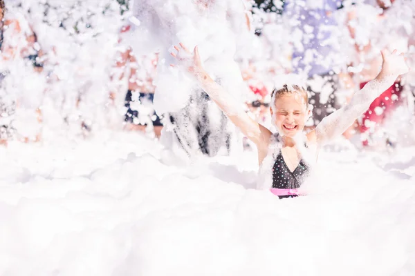 Cute little girl having fun at foam party. — Stockfoto