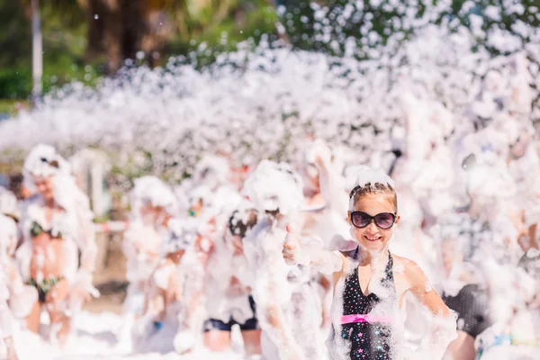 Menina bonito se divertindo na festa de espuma . — Fotografia de Stock