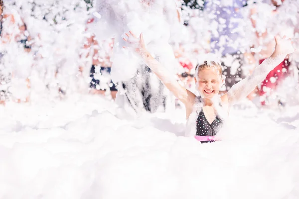 Cute little girl having fun at foam party. 로열티 프리 스톡 이미지