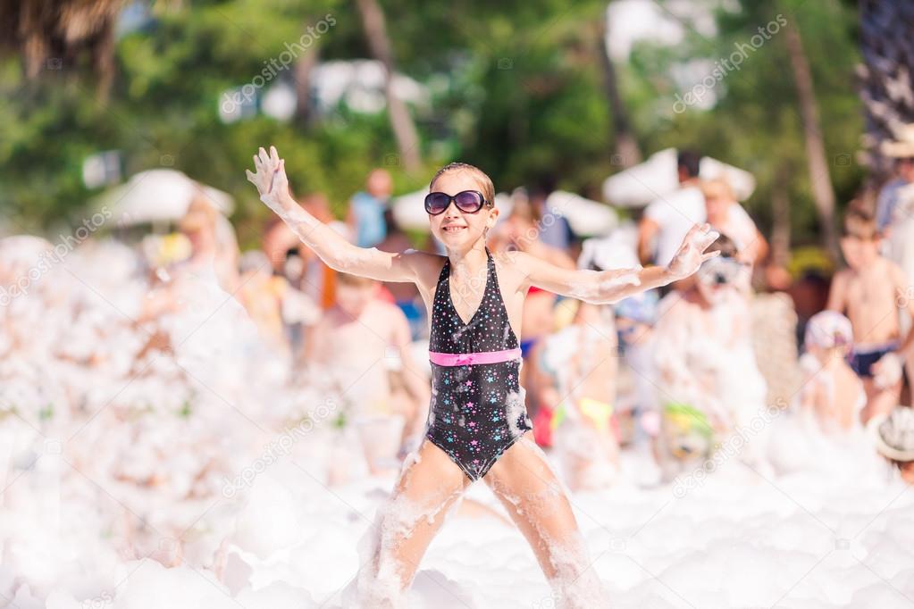 Cute little girl having fun at foam party.