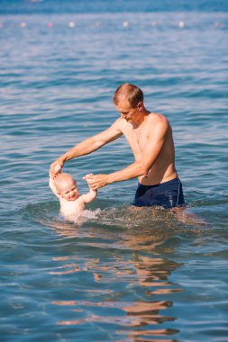 Happy father and baby having fun in the sea