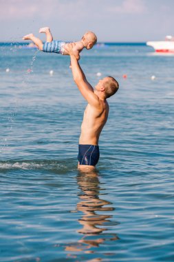 Happy father and baby having fun in the sea