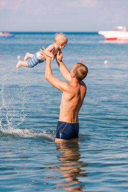 Happy father and baby having fun in the sea