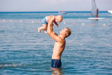 Happy father and baby having fun in the sea
