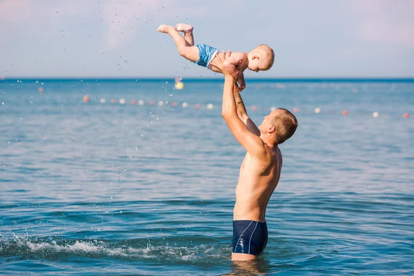 Happy father and baby having fun in the sea — Stock fotografie