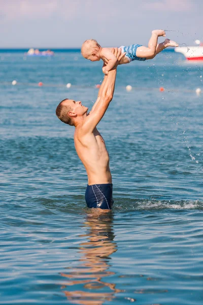 Happy father and baby having fun in the sea — Stock fotografie