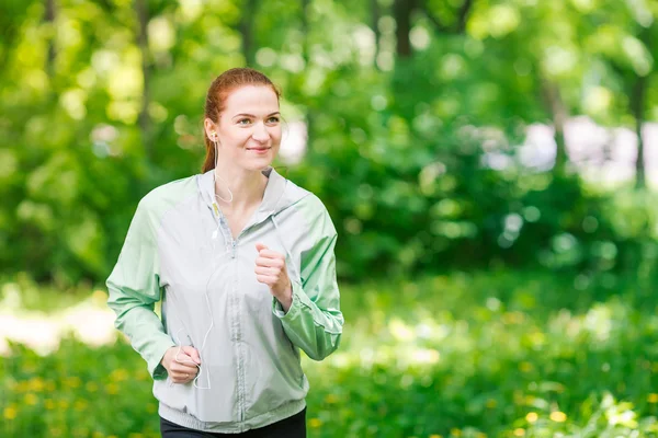 フィットの陽気な女性が公園でジョギング — ストック写真