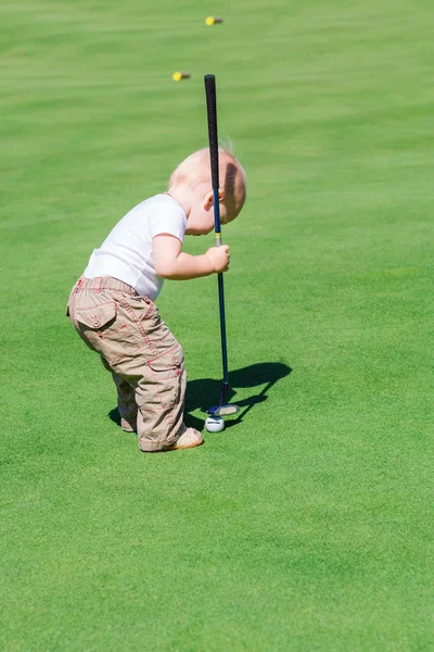 Süßer kleiner Junge spielt Golf auf einem Feld — Stockfoto