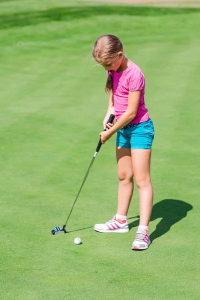 Söt liten flicka spela golf på ett fält — Stockfoto