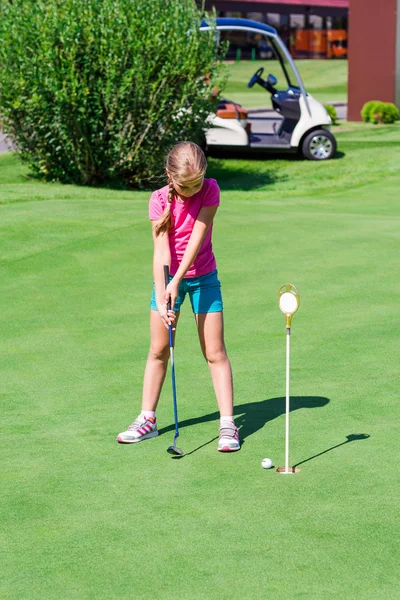 Schattig klein meisje golfen op een veld Stockfoto