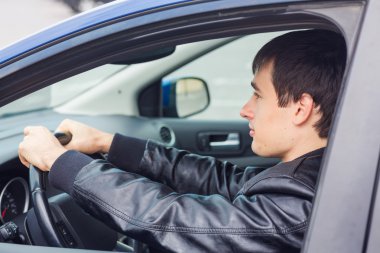 Yakışıklı genç adam arabasında oturuyor.