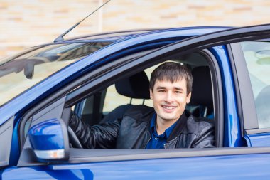 Yakışıklı genç adam arabasında oturuyor.