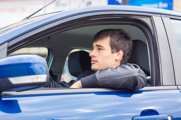 Joven guapo sentado en su coche — Foto de Stock