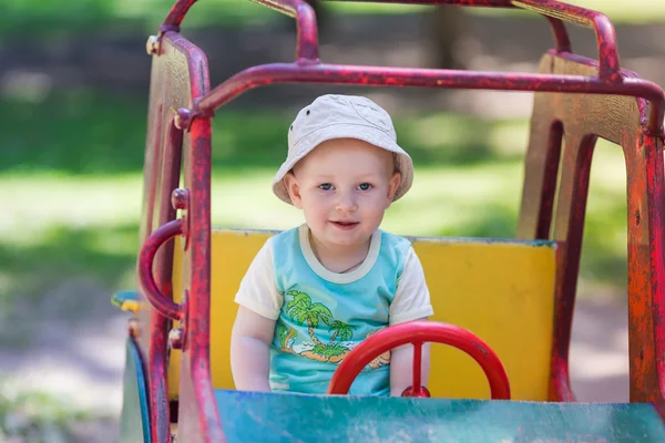 Bambino che guida una macchina giocattolo al parco giochi — Foto Stock