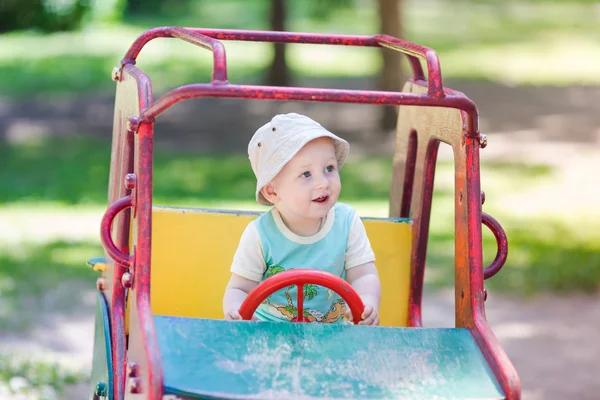 Niño conduciendo un coche de juguete en el patio de recreo — Foto de Stock