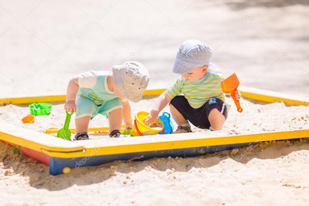 Two baby boys playing with sand