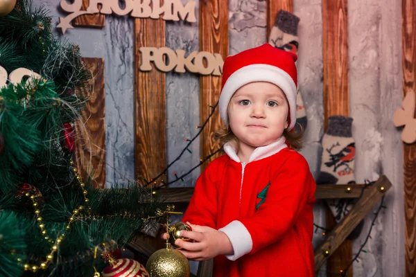 Bebé feliz disfrazado de Santa Claus cerca del árbol de Navidad — Foto de Stock