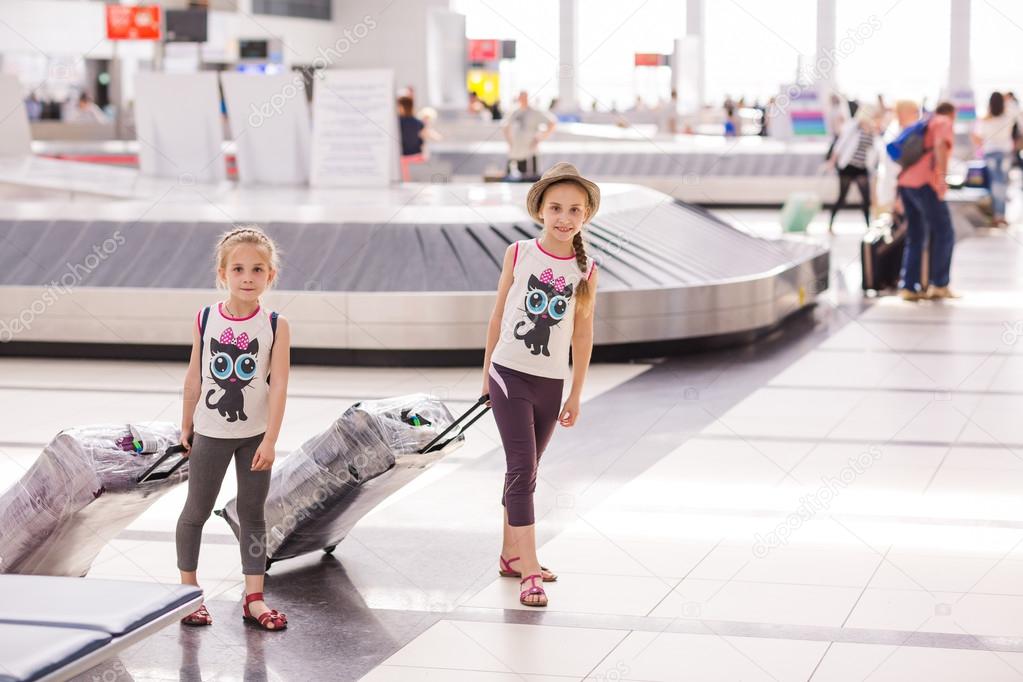 Happy kids with luggage inside airport
