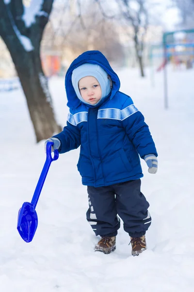 Bonito menino brincando com pá de brinquedo de neve — Fotografia de Stock