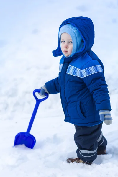 Bonito menino brincando com pá de brinquedo de neve — Fotografia de Stock