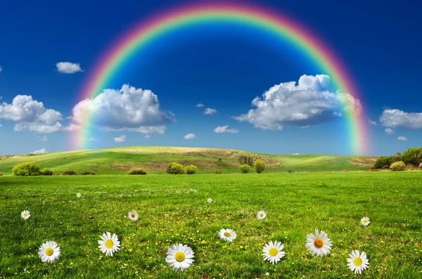 Sunny day with rainbow and fluffy white clouds — Stock Photo, Image