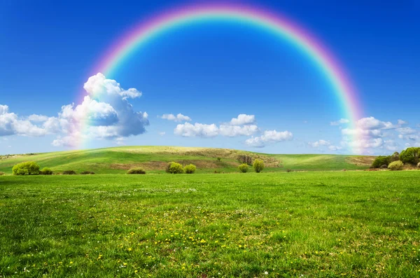 Sunny day with rainbow and fluffy white clouds — Stock Photo, Image