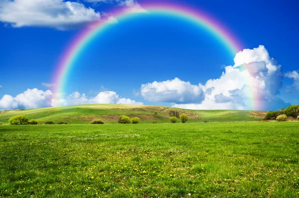 Sunny day with rainbow and fluffy white clouds — Stock Photo, Image