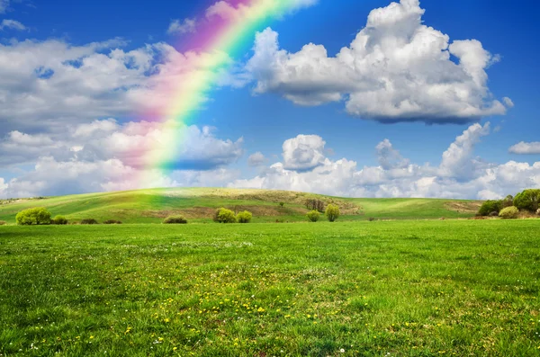 Sunny day with rainbow and fluffy white clouds — Stock Photo, Image
