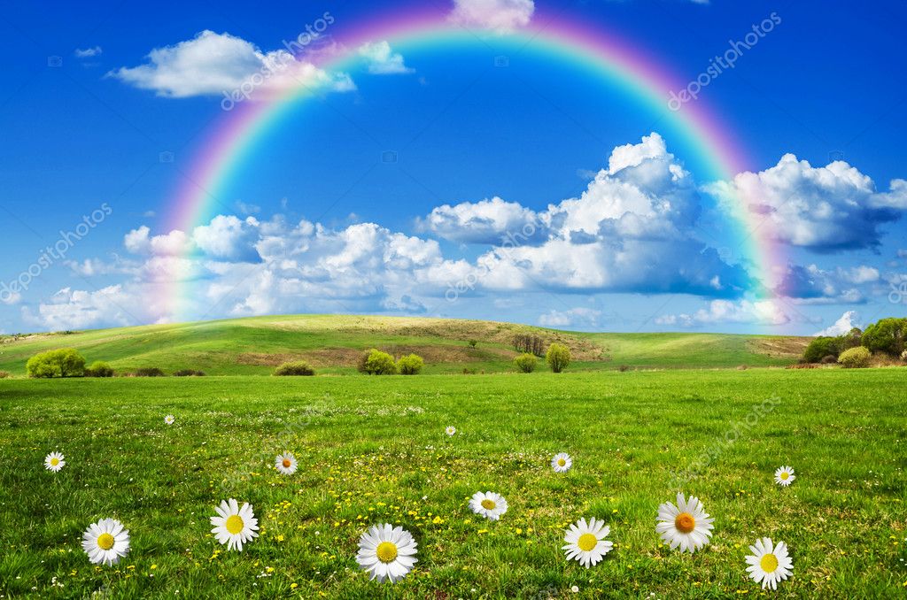 Sunny day with rainbow and fluffy white clouds Stock Photo by