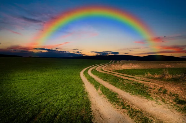 Сельская дорога и радуга ночью — стоковое фото