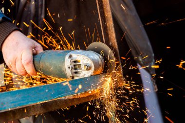 Elektrikli Testere ve Kıvılcımlı Erkek Elleri 'ne yaklaş. Öğütücüyle metal kesen adam, öğütücü tekerlekten kıvılcımlar çıkaran