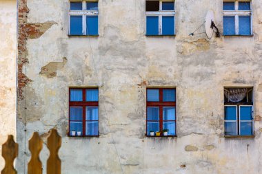 Eski püskü bir duvar, eski pencereler, fakirlik konsepti. Eski apartmanın ön cephesi