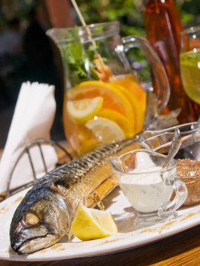 Öğle yemeği güneşli bir günde yaz restoranının terasında servis edilir. Fırında uskumru soslu ve nane aromalı beyaz sangria şarabıyla servis edilir. dikey resim