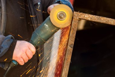 Öğütücü testereyle çalışan adam, aletin görüntüsünü kapat. Elektrikli testere ve kıvılcımlı işçi elleri. Öğütücüyle metal kesen bir işçi