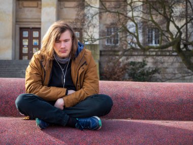 Üzgün genç adam yalnız başına oturur müzik dinler ve rahatlamaya çalışır.