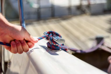Kayık ipli bir adam, deniz düğümlü bir yatçı. Yelkenli teknede ya da yatta düğüm atan insan eli, yakın görüş.