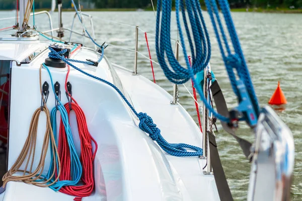 Detail of a sailboat deck with a winch and nylon ropes. Sailing yacht rigging equipment