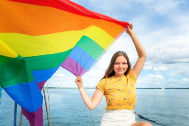 Genç, güzel bir kadın gülümsüyor ve elinde gökkuşağı bayrağı tutuyor. LGBT kavramı