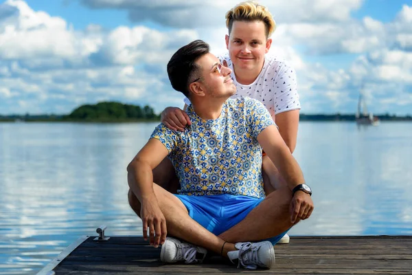 Feliz Sorrindo Gay Casal Sentado Cais Madeira Contra Lago Azul — Fotografia de Stock