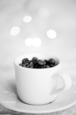 Kahve çekirdeği dolu kahve fincanı, siyah ve beyaz dikey fotoğraf.