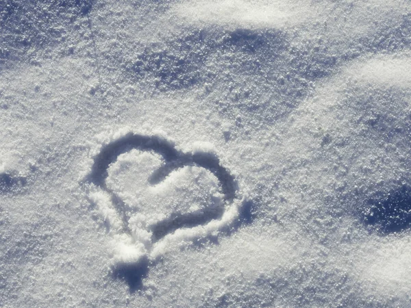 Heart shape painted by finger on fresh white snow. Winter season