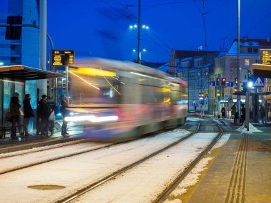 Tramvaydaki insanlar gece hareket bulanıklığında tramvaya yaklaşıyorlar.