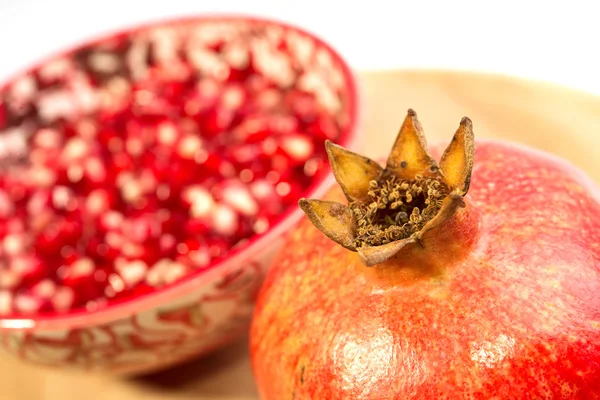 Volné granátového jablka (Punica granatum) semen v červené misky záběr na dřevěné prkénko. izolované na bílém pozadí — Stock fotografie