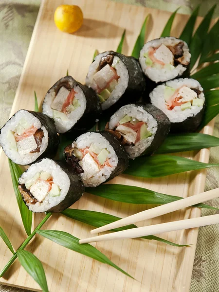 Rollos de sushi en placa de madera —  Fotos de Stock