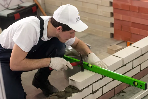 Young bricklayer performs a task of competition