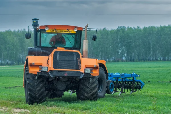 Tractor operator plows the site in rain