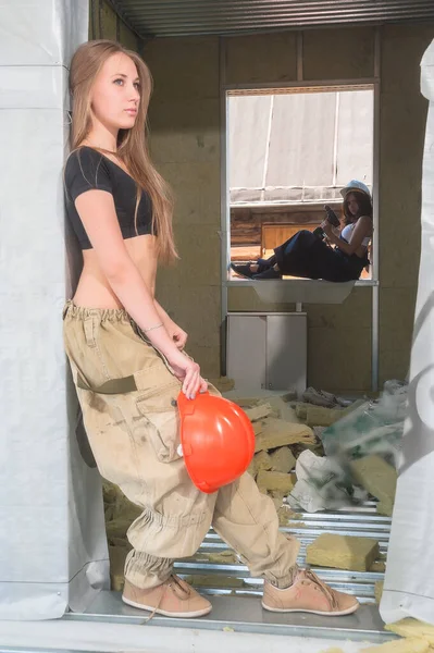 Woman construction worker in hard hat with handsaw