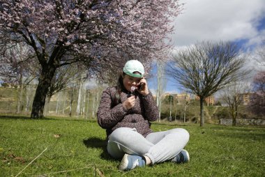 Baharda çiçek ağacına karşı cep telefonuyla konuşan kız.