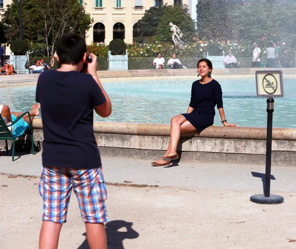 Adolescente chico fotografiando chica, que sentado en la fuente — Foto de Stock